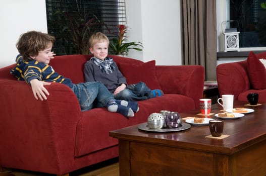 Two brothers are sitting on a couch in the livingroom