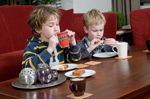 Two brothers drinking and eating something in a livingroom