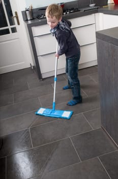 Young boy is learning how to clean a floor
