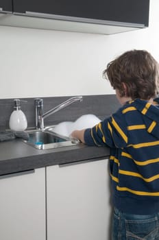 Boy doing the dishes in a modern kitchen
