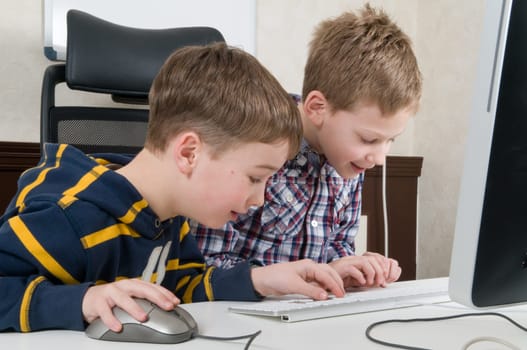 Two friends are having fun while working on a computer.