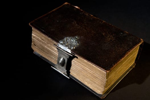 Nice old bible with an old lock on a black background.