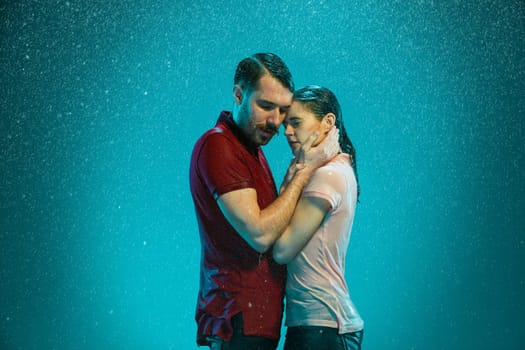 The loving couple kissing in the rain on a turquoise background