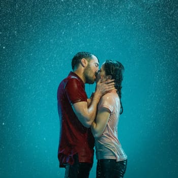 The loving couple kissing in the rain on a turquoise background