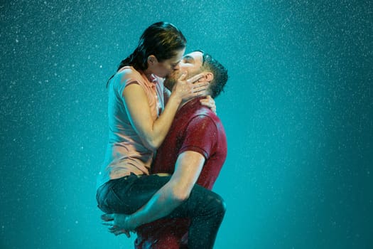 The loving couple kissing in the rain on a turquoise background