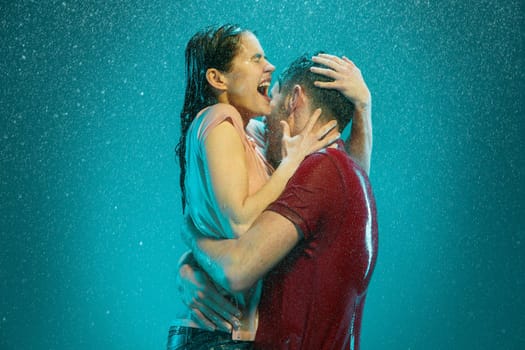 The loving couple kissing in the rain on a turquoise background