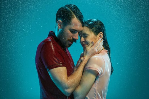 The loving couple kissing in the rain on a turquoise background