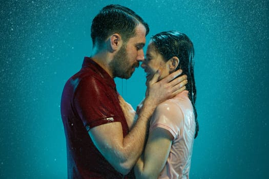 The loving couple kissing in the rain on a turquoise background
