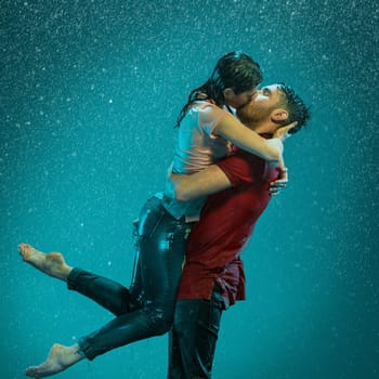 The loving couple kissing in the rain on a turquoise background