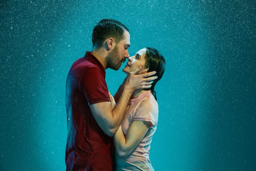 The loving couple kissing in the rain on a turquoise background