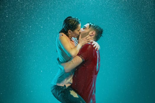 The loving couple kissing in the rain on a turquoise background