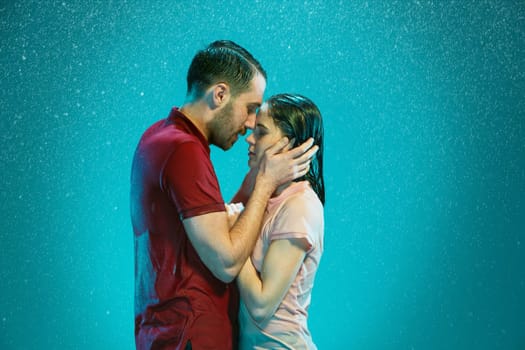 The loving couple kissing in the rain on a turquoise background