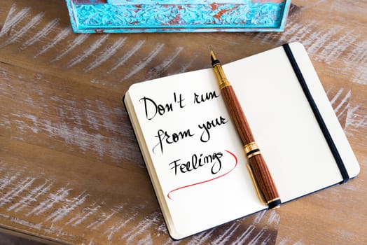 Retro effect and toned image of a fountain pen on a notebook. Handwritten text Don&#39 t Run From Your Feelings as business concept image