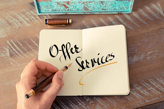 Retro effect and toned image of a woman hand writing a note with a fountain pen on a notebook. Handwritten text Offer Services as business concept image