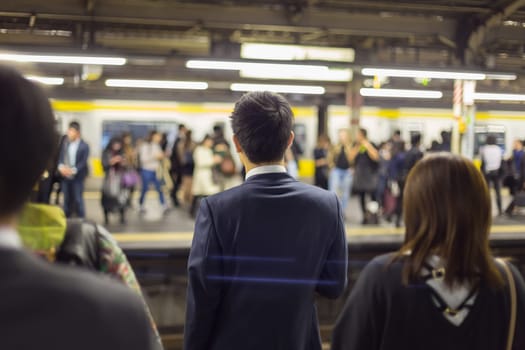 Passengers traveling by Tokyo metro. Business people commuting to work by public transport in rush hour. Shallow depth of field photo.