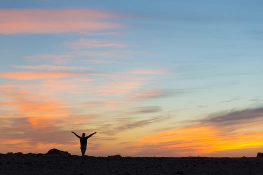 Silhouette of free woman enjoying freedom feeling happy at sunset. Serene relaxing woman in pure happiness and elated enjoyment with arms raised outstretched up.