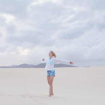 Relaxed woman enjoying freedom feeling happy at beach in the morning. Serene relaxing woman in pure happiness and elated enjoyment with arms outstretched. Copy space.
