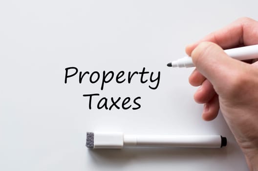 Human hand writing property taxes on whiteboard