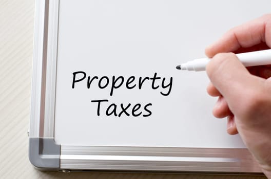 Human hand writing property taxes on whiteboard