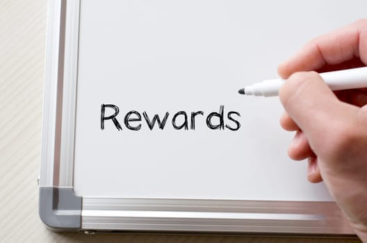 Human hand writing rewards on whiteboard