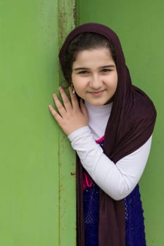 A Close up Portrait of a Beautiful Muslim Girl In Front of a Green Doorway