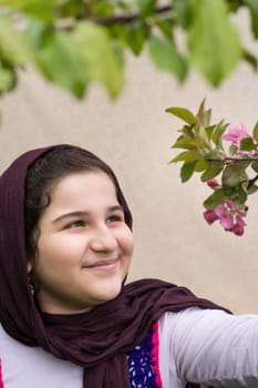 Portrait of a Beautiful Teenage Girl Outdoor in A Garden Looking the Apple Tree buds.