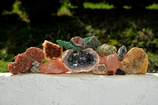 Collection of various minerals and quartz on a white wall against a green background