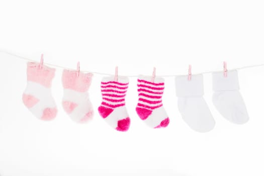 Pink and white baby socks on clothesline, isolated on white background