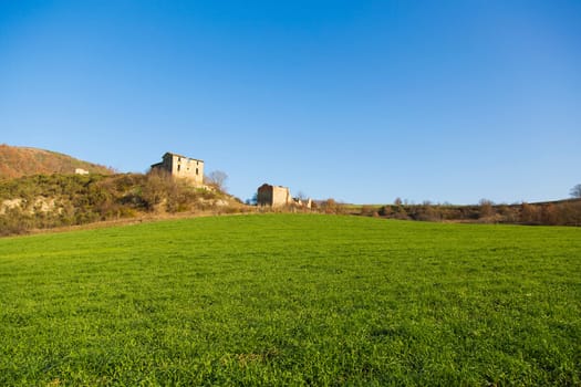 Panoramic view of a field for the agriculture with an old farm in the background