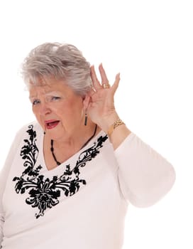 A lovely senior woman in her seventies has problem with hearing, holding.her hand behind her ear, isolated for white background..