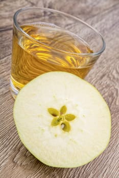 Green apple and juice on a wooden background