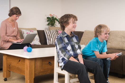 Children are watching tv while mother is working in the background