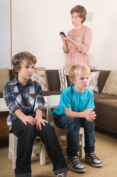 Children are watching tv while mother is calling in the background