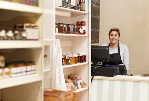 A young deli worker standing behind the counter