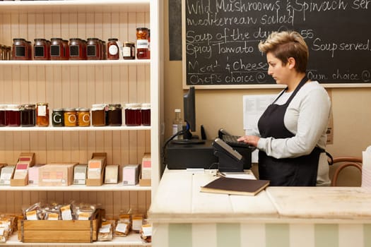 A young deli worker standing behind the counter