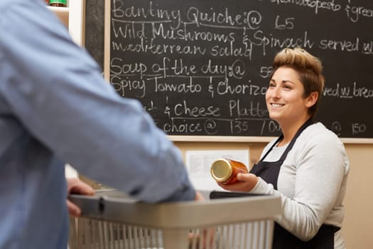 A female deli employee ringing up a young man&#39 s purchases