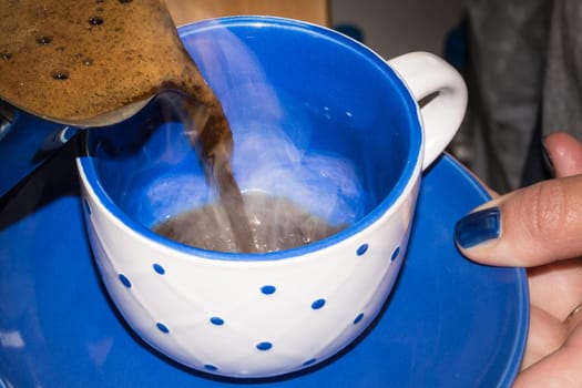 Pouring hot turkish coffee in coffee cup