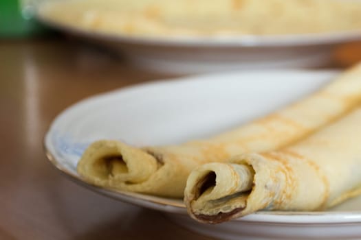 Aranged pancakes on white plate in the kitchen