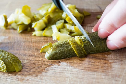 Closeup of pickles beeing cutted with knife.