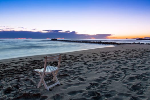 View of a chair on a beach of the Tuscan coast at sunset