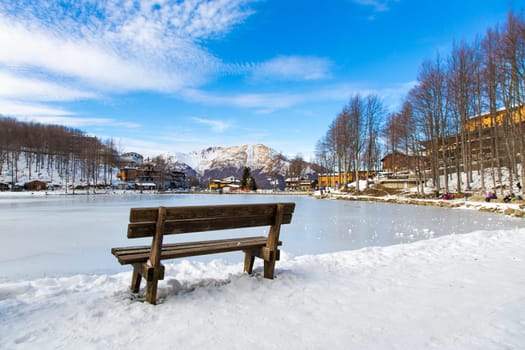 View from the back of a wooden bench in a Tuscan snowy landscape