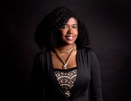 beautiful young black woman is wearing dark dress on grey background