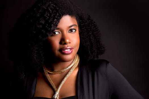 beautiful young black woman is wearing dark dress on grey background