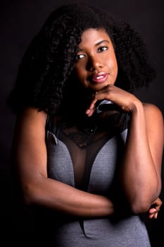 beautiful young black woman is wearing dark dress on grey background
