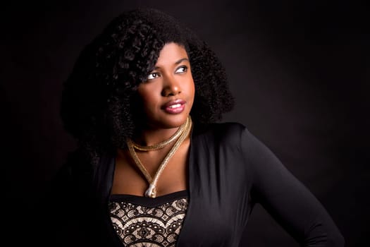 beautiful young black woman is wearing dark dress on grey background