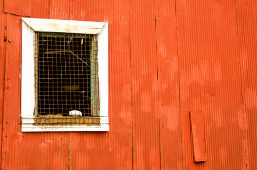 Window on a red corrugated metal wall in Valparaiso, Chile