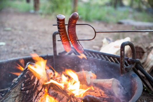 Preparing sausage on campfire