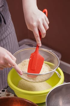 hands sifts flour in to bowl for cake baking