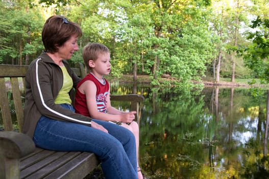 Grandma and her grandson are sitting on a bench.