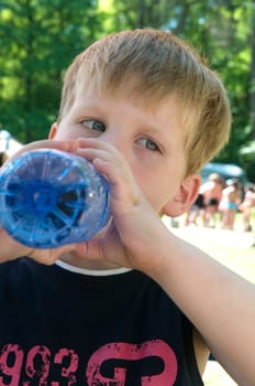 Young boy drinking some nice cold water on a warm sunny day.